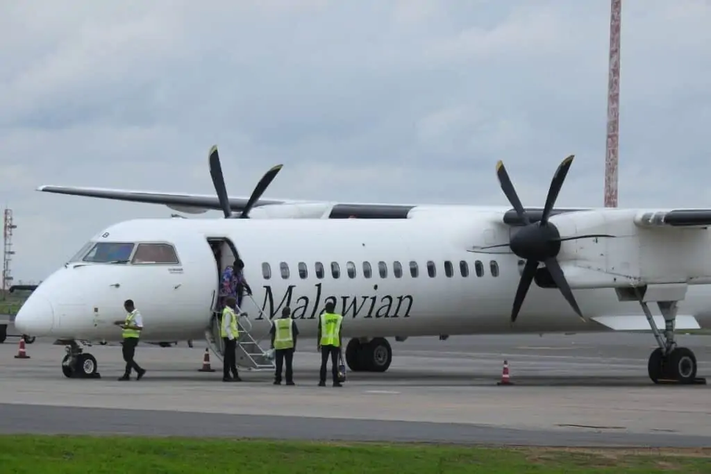 一架马拉维航空公司的小型飞机，门开着，一个人走下台阶