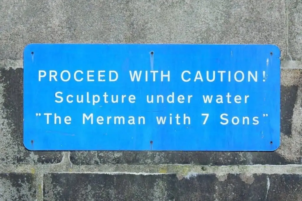 一个蓝色的标志，警告即将经过水下人鱼雕塑的船只