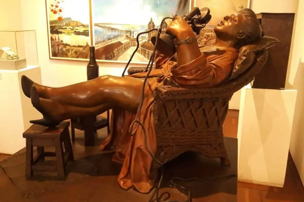 卡塔赫纳现代艺术博物馆的一个女人斜倚在椅子上，翘着脚，手里拿着老式电话的雕塑
