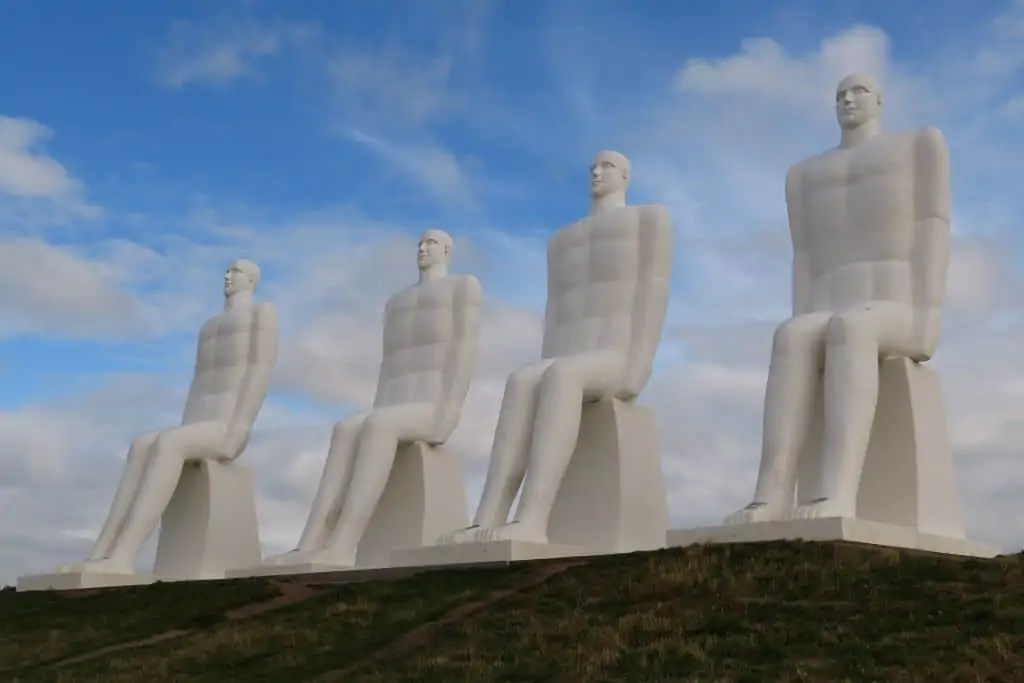 《海边的男人》，一个白色雕塑，四个坐着的男人凝视着大海