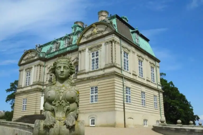 一块石头雕像在前台与哥本哈根的Hermitage狩猎小屋背景。