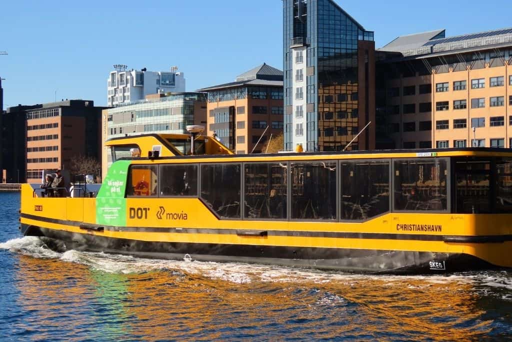 一辆驶过哥本哈根新建建筑的黄色海港巴士。