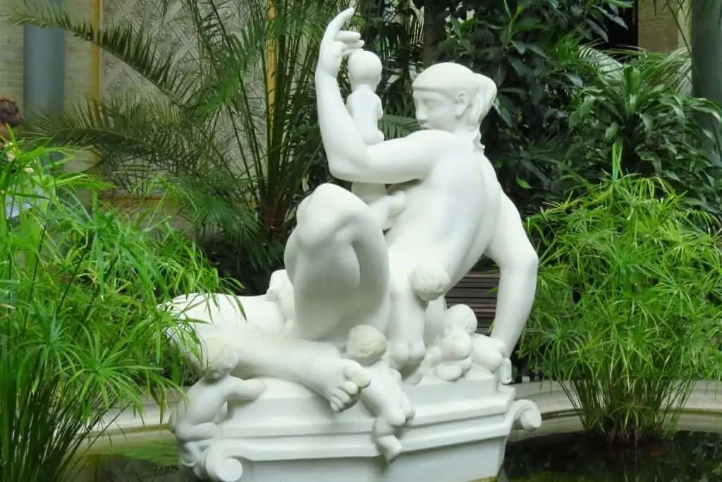 一个纯白的裸女雕塑，几个小孩爬在她的身上。