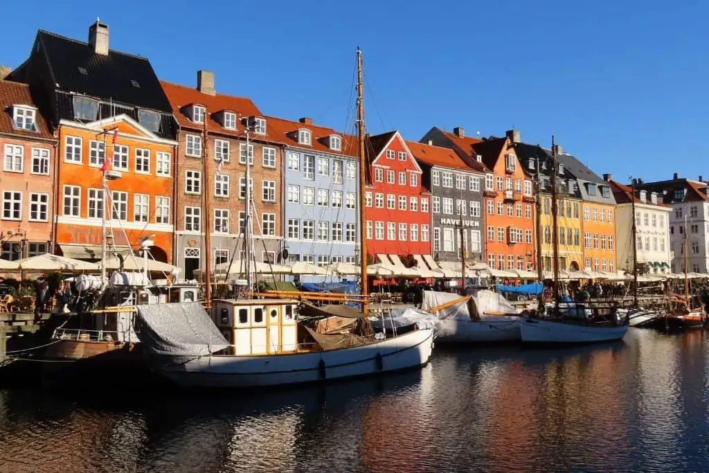 在哥本哈根的尼哈芬，水面上五颜六色的房屋和船只在水中形成倒影。