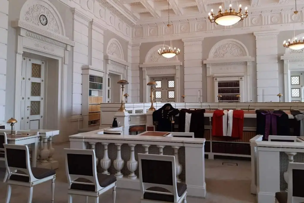 在哥本哈根最高法院内部，有一个白色的房间，里面有白色的桌椅，其中一张桌子上放着最高法院法官的斗篷，