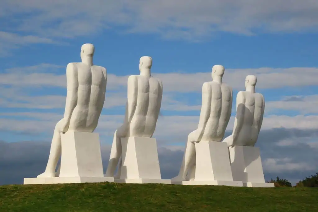 四个9米高的白色雕塑，上面是坐着望向大海的男人。
