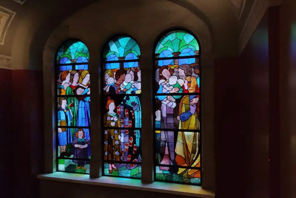 三长,拱形彩色玻璃窗使一个大的图片包括妇女和儿童。